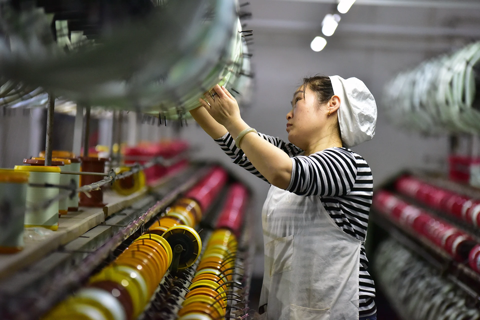 <p> A silk textile worker stands on the production line of a factory in Fuyang, China.</p>