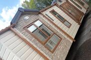 Alt text: An image of a single-story house with brick walls, brown wooden trim, and three glass windows with wooden frames. The 