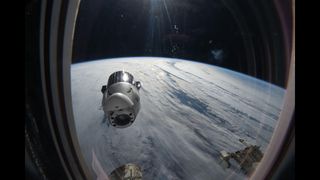A view out of the window of the ISS sees the SpaceX Dragon capsule with Earth in the background.