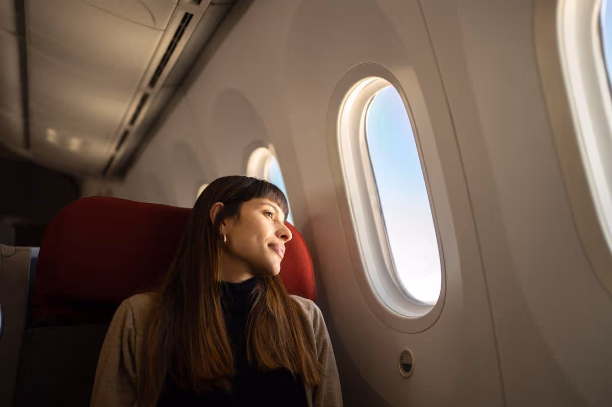 Young woman traveling by plane looking out the window