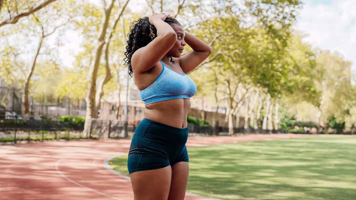 woman outside taking a break from running around an outdoor track